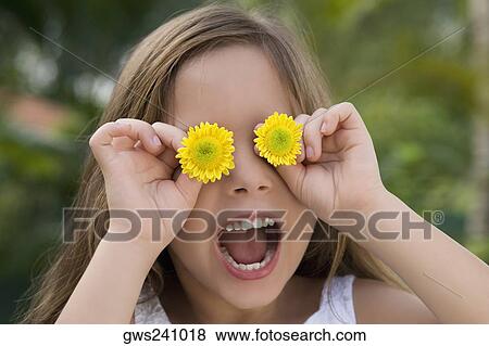 Close-up of a girl holding flowers over her eyes View Large Photo Image Stock Photo - Close-up of a girl holding flowers over her eyes. Fotosearch