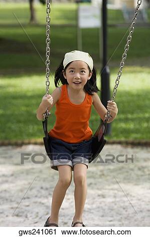 Stock Image - Girl swinging on a chain swing ride and smiling. Fotosearch