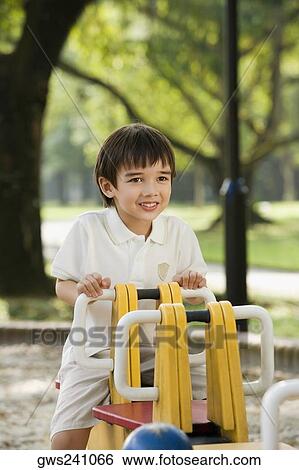 Stock Photograph - Portrait of a boy sitting on a ride and smiling in a park. Fotosearch