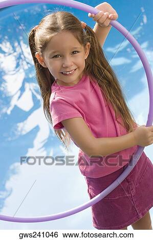 Stock Photograph - Portrait of a girl holding a plastic hoop and smiling. Fotosearch