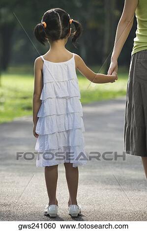 Rear view of a girl holding her mother's hand View Large Photo Image Stock Image - Rear view of a girl holding her mother's hand. Fotosearch
