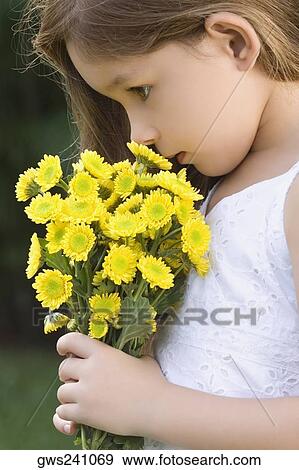 Side profile of a girl holding a bunch of flowers and smelling View Large Photo Image Stock Photo - Side profile of a girl holding a bunch of flowers and smelling. Fotosearch
