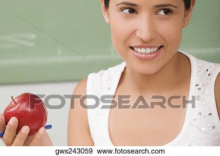 Close-up of a female teacher holding an apple and smiling View Large Photo Image Stock Photo - Close-up of a female teacher holding an apple and smiling. Fotosearch
