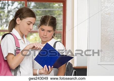 Close-up of a schoolgirl showing her textbook to another schoolgirl View Large Photo Image Stock Photo - Close-up of a schoolgirl showing her textbook to another schoolgirl. Fotosearch