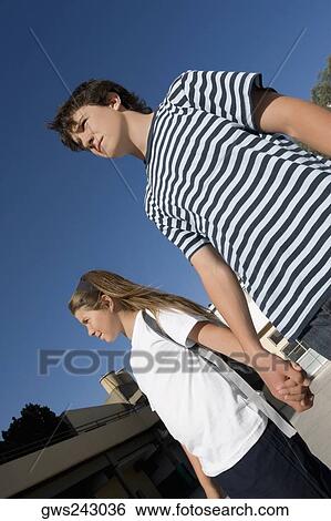 Stock Photograph - Low angle view of a teenage boy holding hands of his sister. Fotosearch
