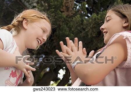 Low angle view of two schoolgirls playing clapping game and smiling View Large Photo Image Stock Image - Low angle view of two schoolgirls playing clapping game and smiling. Fotosearch