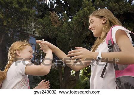 Low angle view of two schoolgirls playing clapping game and smiling View Large Photo Image Stock Image - Low angle view of two schoolgirls playing clapping game and smiling. Fotosearch