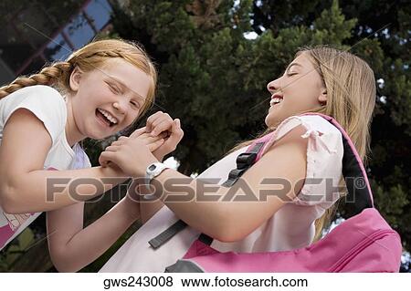 Low angle view of two schoolgirls playing clapping game and smiling View Large Photo Image Stock Photo - Low angle view of two schoolgirls playing clapping game and smiling. Fotosearch