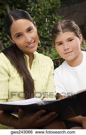 Portrait of a female teacher holding a file with a schoolgirl beside her and smiling View Large Photo Image Stock Photograph - Portrait of a female teacher holding a file with a schoolgirl beside her and smiling. Fotosearch