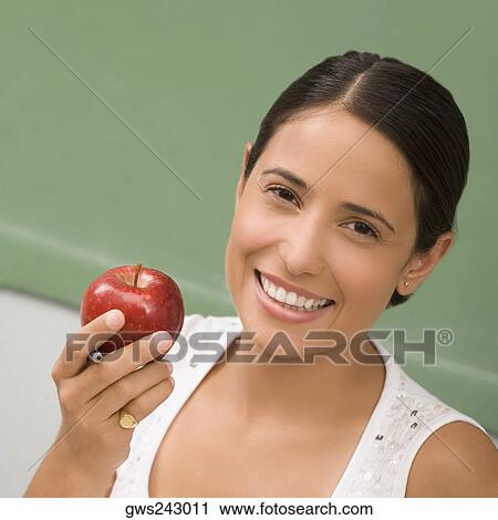 Portrait of a female teacher holding an apple and smiling View Large Photo Image Stock Image - Portrait of a female teacher holding an apple and smiling. Fotosearch