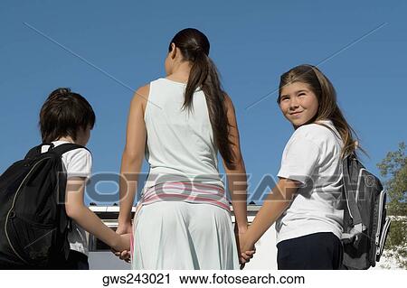Rear view of a mid adult woman holding hands of her two children View Large Photo Image Stock Image - Rear view of a mid adult woman holding hands of her two children. Fotosearch