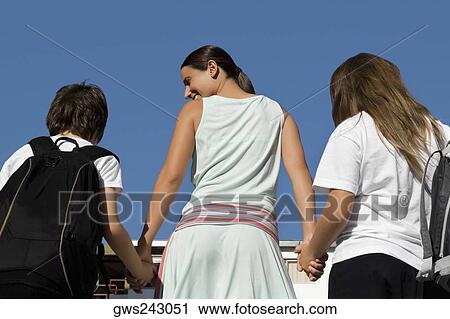 Rear view of a mid adult woman holding hands of her two children View Large Photo Image Stock Image - Rear view of a mid adult woman holding hands of her two children. Fotosearch