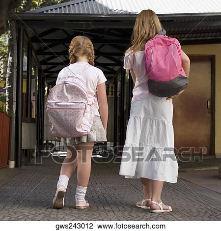 Rear view of two schoolgirls carrying schoolbags and walking View Large Photo Image Stock Image - Rear view of two schoolgirls carrying schoolbags and walking. Fotosearch