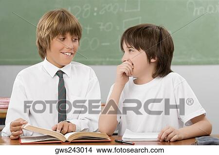 Two schoolboys looking at each other and smiling in a classroom View Large Photo Image Picture - Two schoolboys looking at each other and smiling in a classroom. Fotosearch