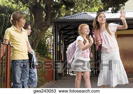 Two schoolgirls waving their hands with two schoolboys looking at them View Large Photo Image Stock Image - Two schoolgirls waving their hands with two schoolboys looking at them. Fotosearch