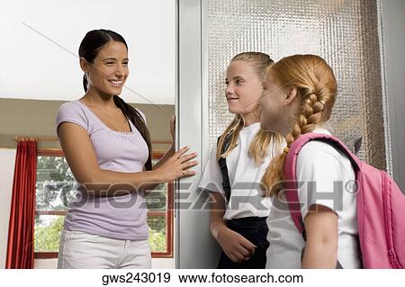 Two schoolgirls with a female teacher looking at each other and smiling View Large Photo Image Stock Photo - Two schoolgirls with a female teacher looking at each other and smiling. Fotosearch