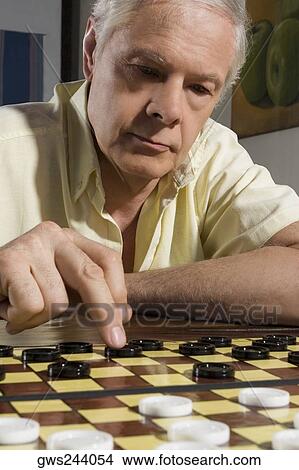 Picture - Close-up of a senior man playing checkers. Fotosearch