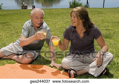 Senior couple holding glasses of juice at picnic View Large Photo Image Stock Photo - Senior couple holding glasses of juice at picnic. Fotosearch