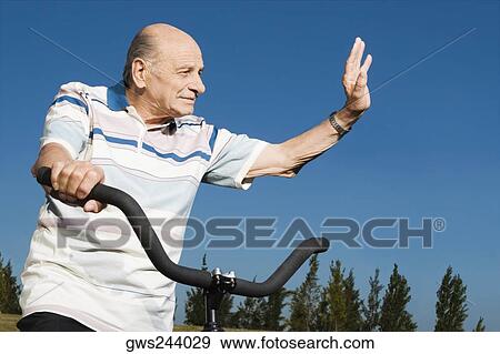 Senior man on a bicycle and waving his hand View Large Photo Image Stock Photo - Senior man on a bicycle and waving his hand. Fotosearch