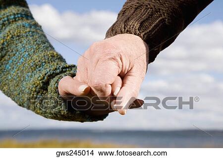 Close-up of a couple holding hands of each other View Large Photo Image Picture - Close-up of a couple holding hands of each other. Fotosearch