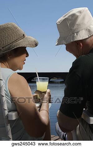 Rear view of a senior couple sitting at the lakeside View Large Photo Image Stock Image - Rear view of a senior couple sitting at the lakeside. Fotosearch