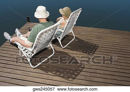 Rear view of a senior couple sitting on chairs at the lakeside View Large Photo Image Stock Photo - Rear view of a senior couple sitting on chairs at the lakeside. Fotosearch