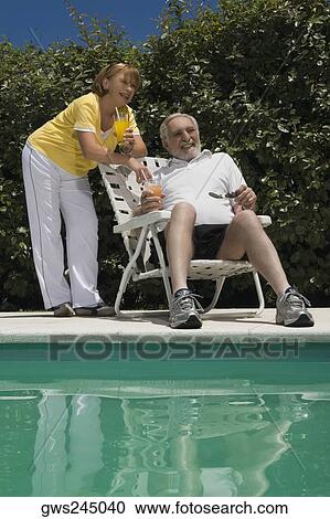 Senior couple holding glasses of juice at the poolside View Large Photo Image Stock Image - Senior couple holding glasses of juice at the poolside. Fotosearch