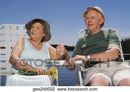 Senior couple sitting at the lakeside with holding hands of each other View Large Photo Image Stock Image - Senior couple sitting at the lakeside with holding hands of each other. Fotosearch