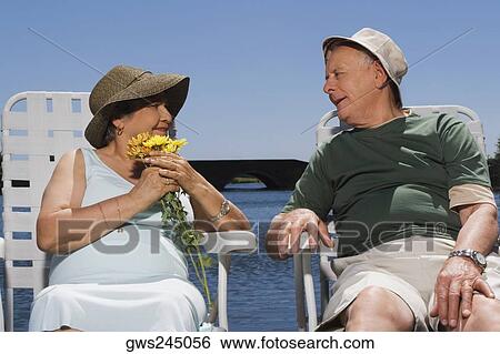 Senior couple sitting at the lakeside and looking at each other View Large Photo Image Stock Photograph - Senior couple sitting at the lakeside and looking at each other. Fotosearch