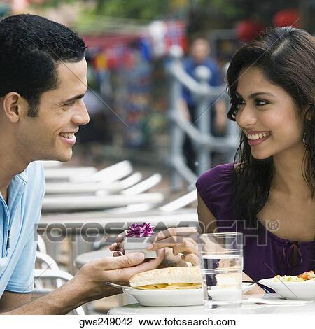 Mid adult man proposing to a young woman at a sidewalk cafe View Large Photo Image Stock Image - Mid adult man proposing to a young woman at a sidewalk cafe. Fotosearch
