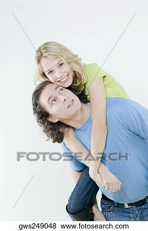 Stock Photo - Young woman riding piggyback on a young man. Fotosearch