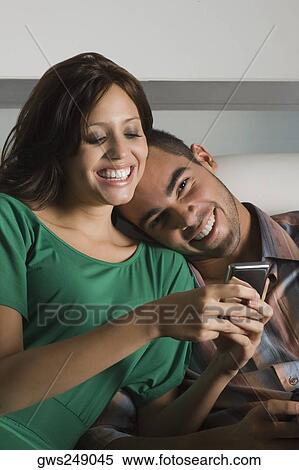 Young woman using a mobile phone and a young man leaning on her shoulder View Large Photo Image Stock Photography - Young woman using a mobile phone and a young man leaning on her shoulder. Fotosearch