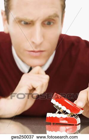 Businessman looking at dentures View Large Photo Image Stock Photo - Businessman looking at dentures. Fotosearch