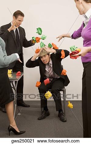 Businessman protecting himself from colleagues throwing paper balls View Large Photo Image Stock Image - Businessman protecting himself from colleagues throwing paper balls. Fotosearch