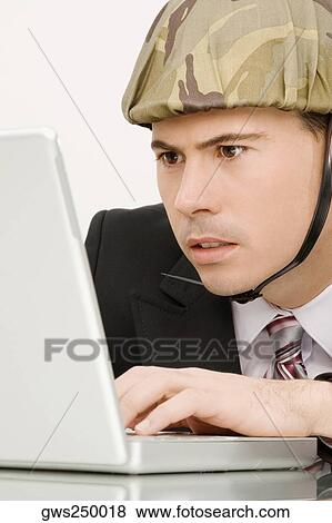 Close-up of a businessman wearing an army helmet and working on a laptop View Large Photo Image Stock Photo - Close-up of a businessman wearing an army helmet and working on a laptop. Fotosearch