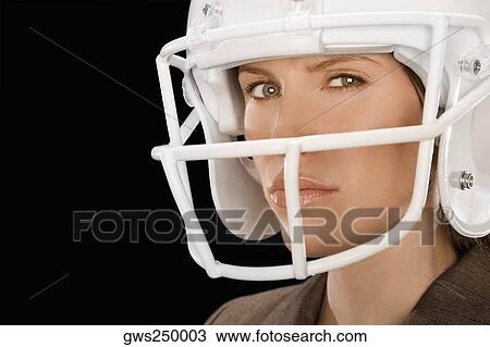Stock Image - Close-up of a businesswoman wearing a football helmet. Fotosearch