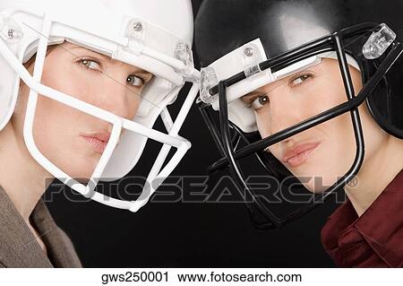 Stock Image - Close-up of two businesswomen wearing football helmets. Fotosearch