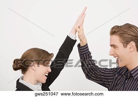 Stock Photo - Businessman and a businesswoman giving high-five and smiling. Fotosearch
