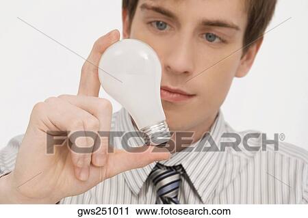 Stock Image - Close-up of a businessman holding a light bulb. Fotosearch