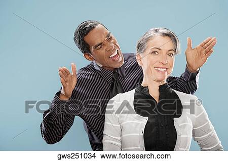 Portrait of a businesswoman smiling with a businessman shouting at her View Large Photo Image Picture - Portrait of a businesswoman smiling with a businessman shouting at her. Fotosearch