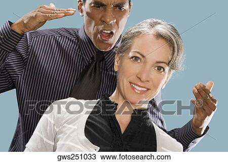 Portrait of a businesswoman smiling with a businessman shouting at her View Large Photo Image Stock Image - Portrait of a businesswoman smiling with a businessman shouting at her. Fotosearch