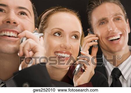 Business executives talking on mobile phones and smiling View Large Photo Image Stock Image - Business executives talking on mobile phones and smiling. Fotosearch