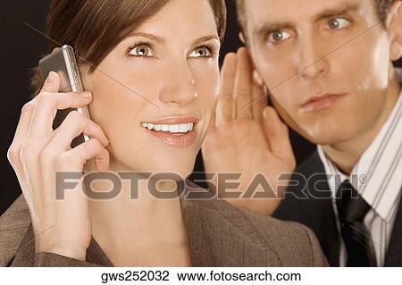 Businesswoman talking on a mobile phone and a businessman listening to her View Large Photo Image Stock Image - Businesswoman talking on a mobile phone and a businessman listening to her. Fotosearch