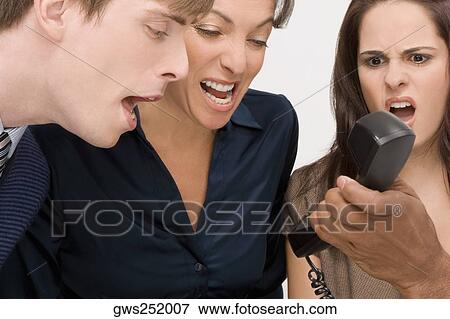 Close-up of a person's hand holding a telephone with three business executives shouting View Large Photo Image Stock Photo - Close-up of a person's hand holding a telephone with three business executives shouting. Fotosearch