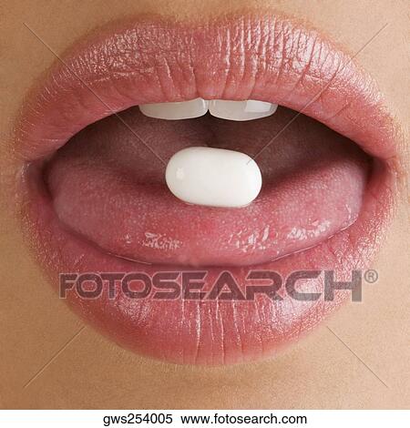 Stock Photography - Close-up of a pill on a young woman's tongue. Fotosearch