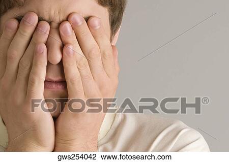 Close-up of a young man covering his eyes with his hands View Large Photo Image Stock Image - Close-up of a young man covering his eyes with his hands. Fotosearch