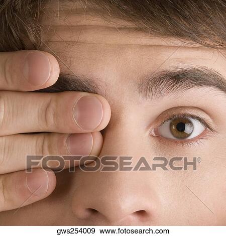 Close-up of a young man covering his one eye View Large Photo Image Stock Photo - Close-up of a young man covering his one eye. Fotosearch