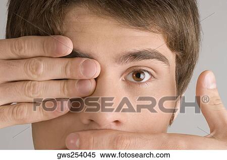 Close-up of a young man covering his mouth and his eye with his hands View Large Photo Image Stock Photography - Close-up of a young man covering his mouth and his eye with his hands. Fotosearch