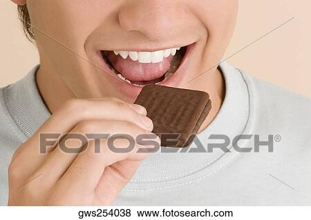 Close-up of a young man eating a biscuit View Large Photo Image Stock Photo - Close-up of a young man eating a biscuit. Fotosearch