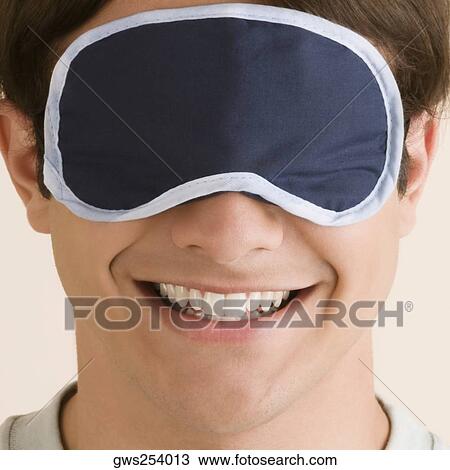 Stock Image - Close-up of a young man wearing an eye mask. Fotosearch